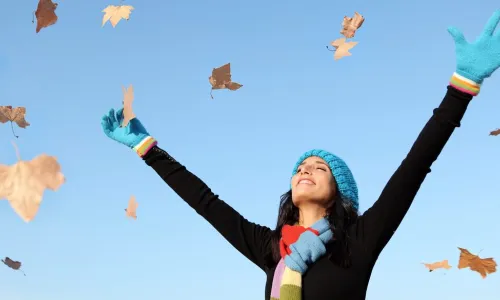 woman throwing fall leaves in the air