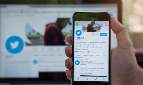 hand holding smartphone displaying Twitter homepage