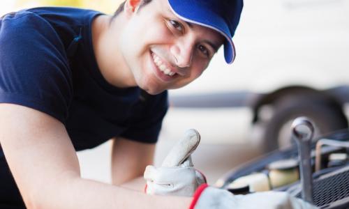 smiling mechanic tunes up a car engine