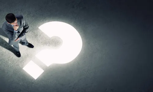 business man standing in shadow with a lit question mark in front of him