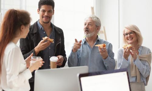 group of mixed age executives talking while eating pizza