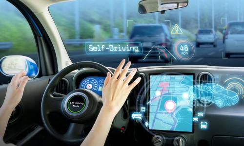 woman at steering wheel with self driving mode on her car's screen