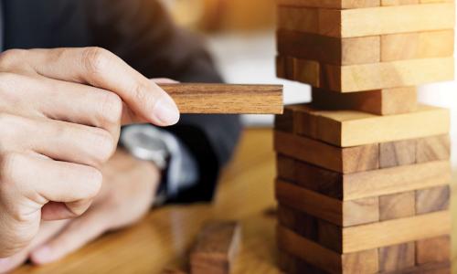 businessman carefully playing Jenga