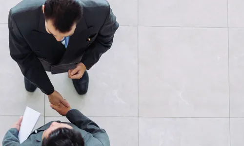 overhead view of two businessmen shaking hands in agreement