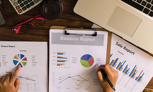 Person reviewing business reports with graphs and charts at a desk