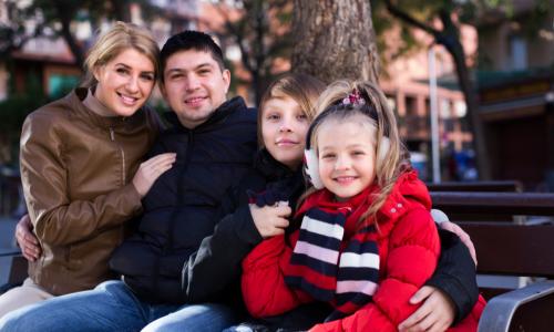 Average family with two kids sitting on bench outdoors