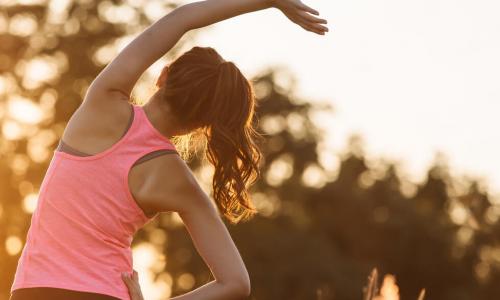 young woman warming up outdoors by stretching