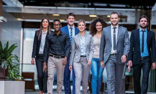 group of smiling young professionals walking together out of an office toward the camera