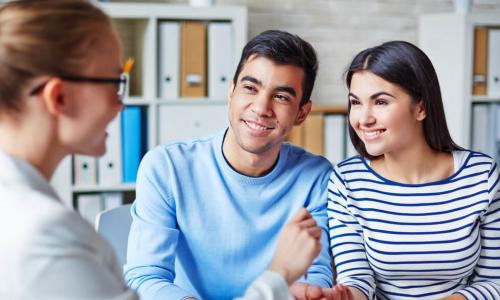 Happy young couple making deal with an agent