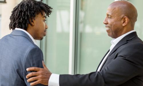 senior executive mentor shaking hands with young trainee