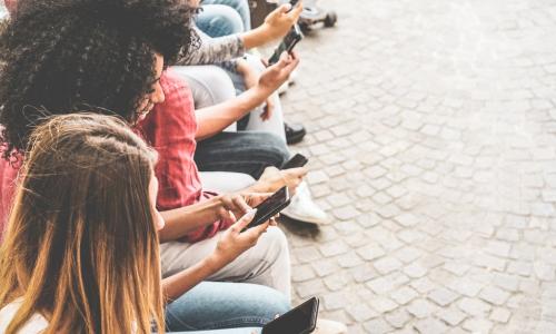 group of young generation z members watching their smartphones