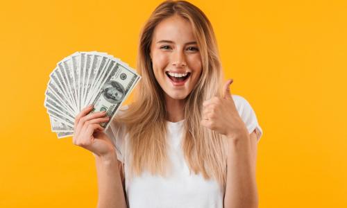 woman on a yellow background holding fanned out money