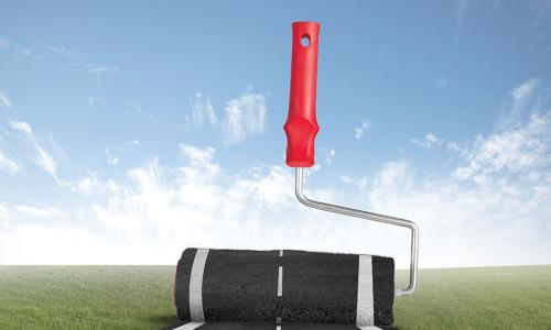 giant paint roller applying road pavement to landscape