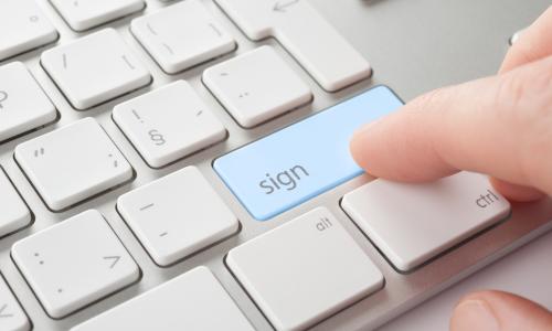 Fingers choosing the sign button on a keyboard