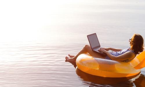 female workaholic using laptop while floating on a lake