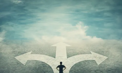 man surveys his options at a three-way fork in a cobblestone road