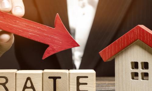 man holding arrow pointing down toward a house over the word rates in wooden blocks