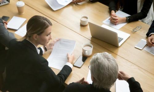 two groups of people on opposite sides of a table negotiating contract