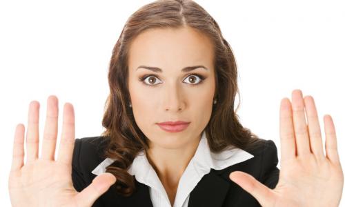 Serious young woman with hands up in stop gesture