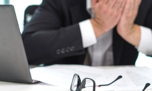 stressed out businessman holds his head in his hands at the office