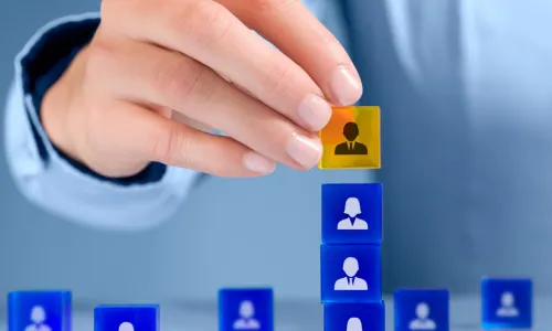 person stacking blue and yellow blocks with people icons