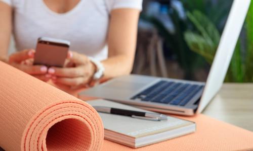 woman with laptop phone and yoga mat