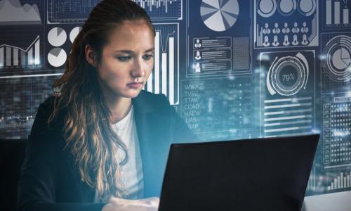 female executive using laptop in front of wall of figures