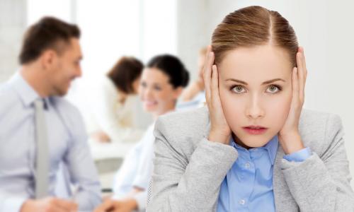 stressed young businesswoman covers her ears in busy office