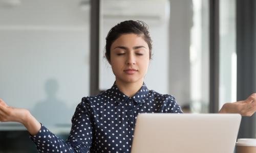 female executive meditating at her desk