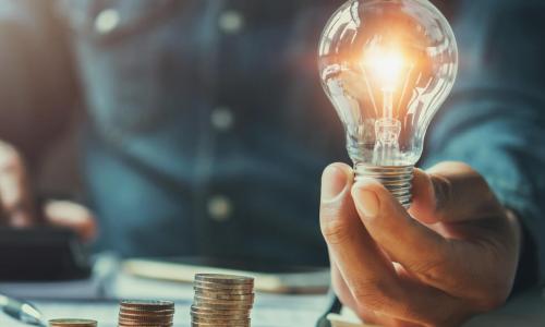 business man hand holding lightbulb with using calculator to calculate and money stack