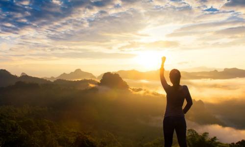 woman in sunset at top of mountain