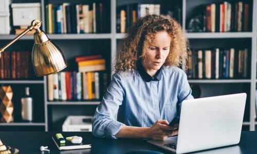 woman learning with laptop and phone in home office library office