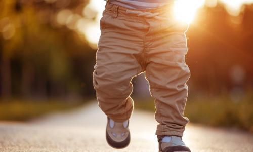 baby walking on sidewalk with sun