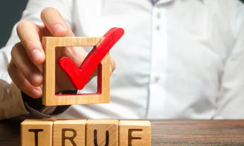 man holds red check mark over the word true
