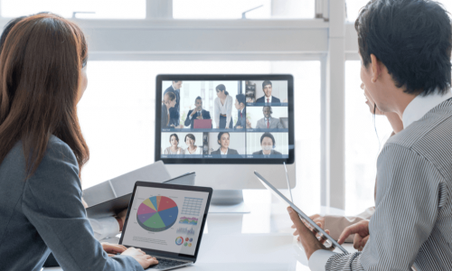 coworkers around table in office video conference with remote workers