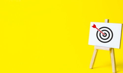 red arrow on target on easel on yellow background