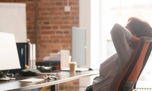 businesswoman leans back in office chair to destress and take mental break