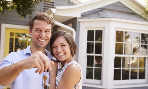 couple with keys standing outside new home