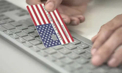 man making online payment using credit card with U.S. flag keyboard