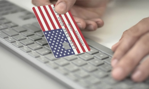 man making online payment using credit card with U.S. flag keyboard