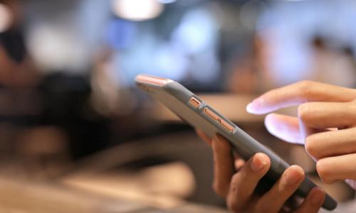 woman using a mobile smartphone on wooden table at night