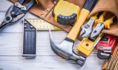 hammer and leather belt with pouches full of tools on wood surface