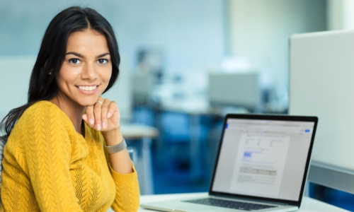 smiling female lending officer in yellow sweater with laptop