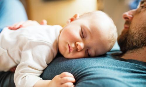 baby sleeps on her father's chest