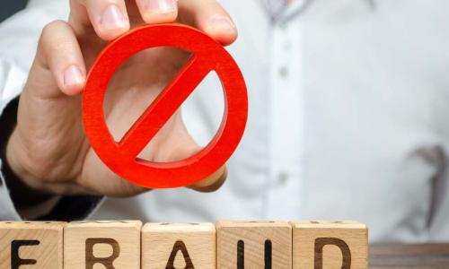 A man holds a red NO prohibition symbol over word fraud