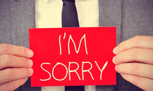 man with red sign saying I’m sorry