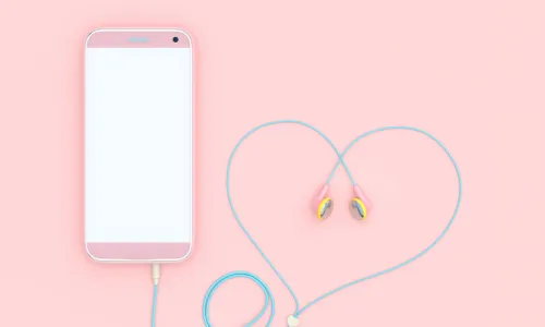 pink smartphone with earbud headphone cord curled into a heart shape