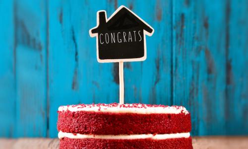 chalkboard congrats sign in shape of house stuck into a celebratory red velvet cake