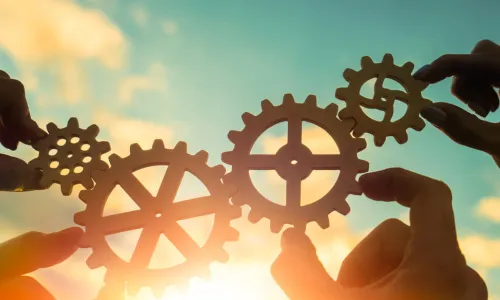 executives hold up gears together in the sunset