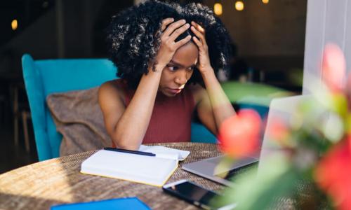 tired young Black woman studying online learning on laptop and notebook